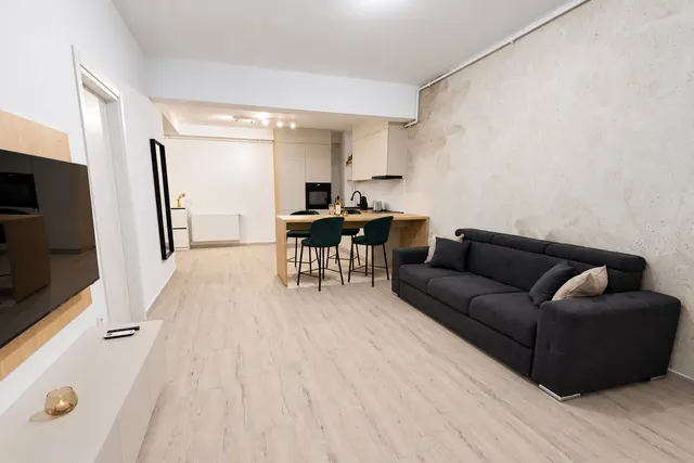 Living deschis cu canapea gri, masă cu scaune verzi și bucătăria în fundal, la Casa del Mar, Mamaia Nord