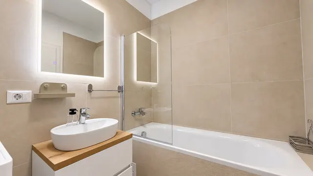 Baie cu cadă, oglindă luminată și mobilier cu blat din lemn, la Torontal, Timișoara